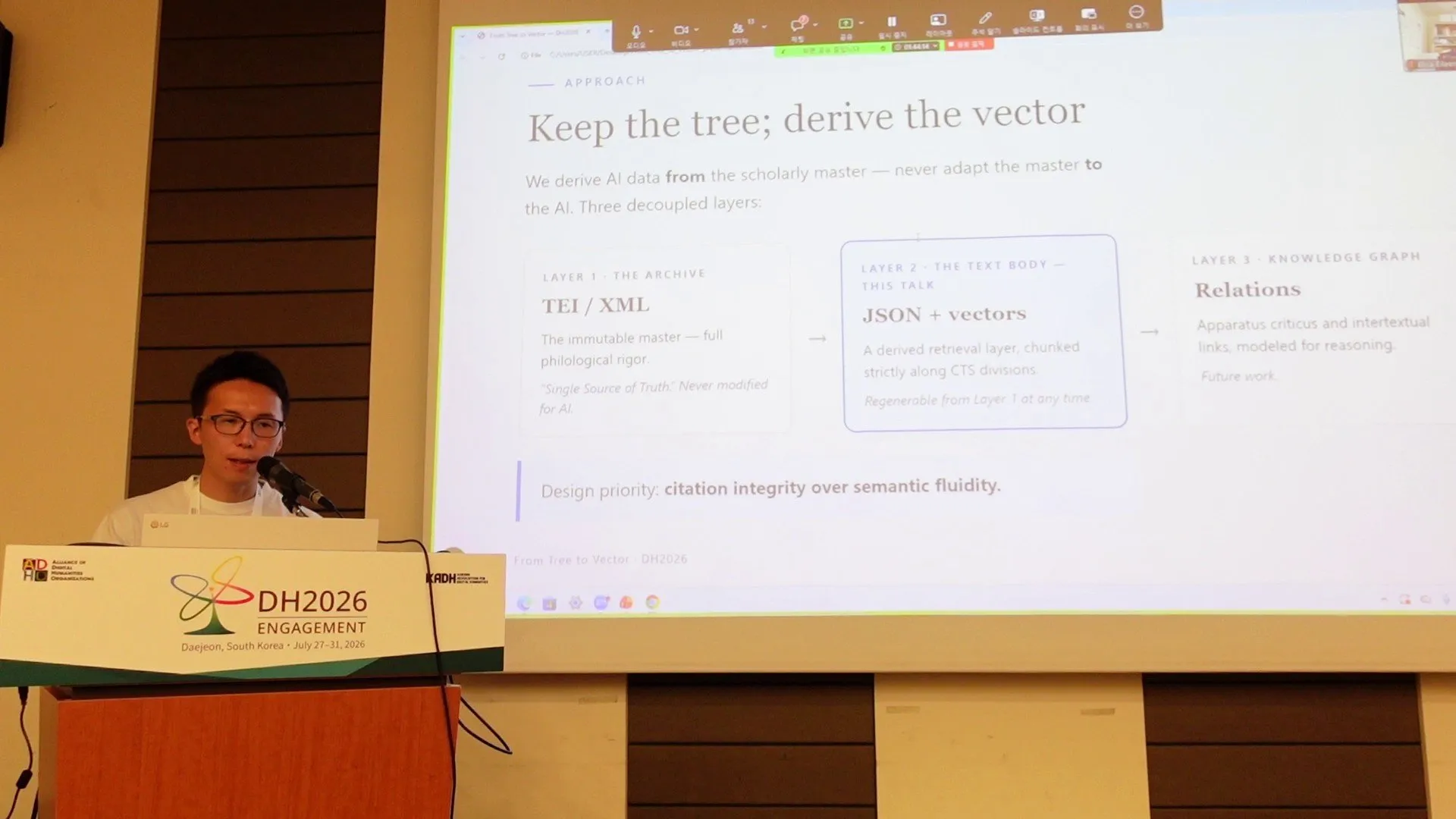 Naoya Iwata presenting at the DH2026 podium with the slide "Keep the tree; derive the vector"