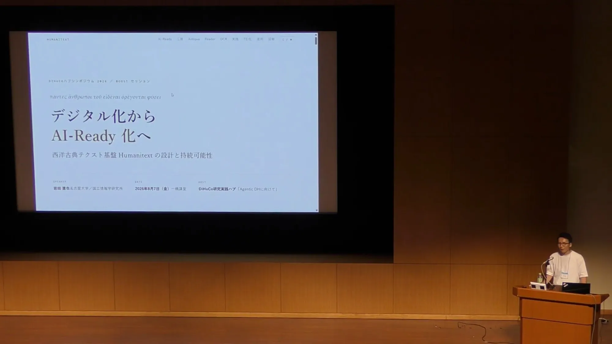 Naoya Iwata speaking at Hitotsubashi Hall with the title slide "From Digitization to AI-Readiness" on screen