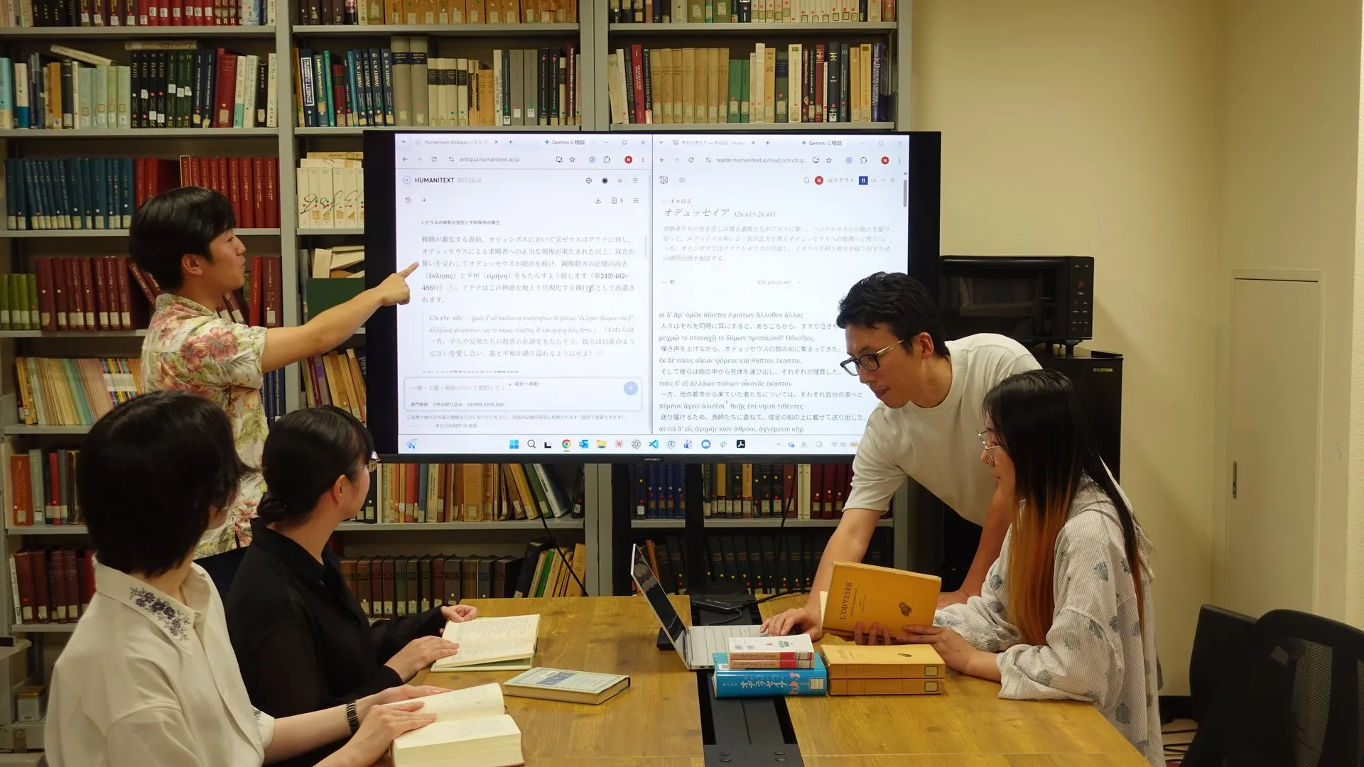 研究室のモニターにHumanitext AntiquaとReaderを映し、校訂本と翻訳を机に広げて議論するプロジェクトメンバー